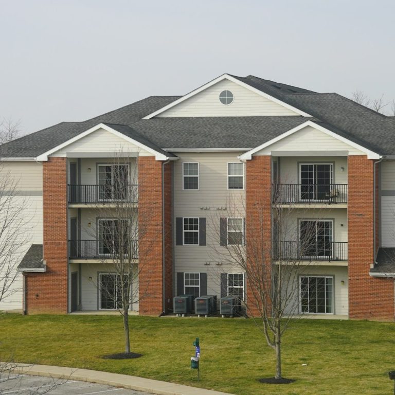 Three-story apartment building with balconies and landscaped grass area.